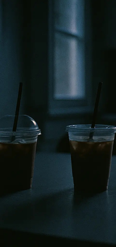 Two cold coffee cups resting on a kitchen table.
