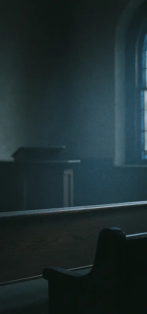 An empty back pew inside a church with morning light shining through stained glass windows.
